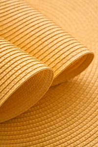 Macro detail of high-density orange woven PP placemat showing spiral texture and heat resistance