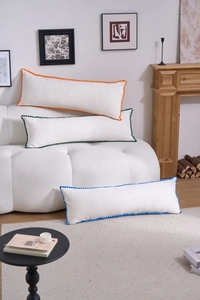 Detailed view of long lumbar pillows with colorful pom-pom trims on a modern white sofa