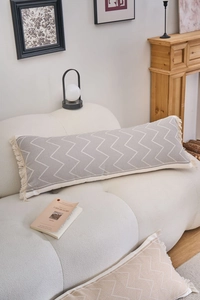 Close-up of a long lumbar pillow with gray geometric patterns and cream-colored side tassels