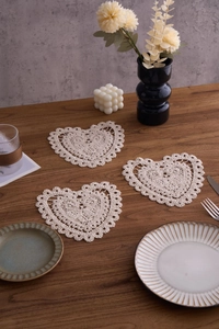 Detailed view of three heart-shaped crochet coasters with delicate cotton lace patterns
