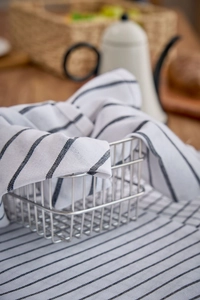 Close-up of a soft white cotton napkin with black stripes in a silver wire storage basket