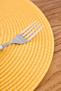Close-up of yellow woven round placemat showing detailed heat-resistant fiber texture