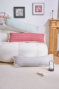 Détail de longs coussins en jacquard tissé avec motifs géométriques et bords à franges