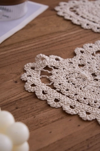 Close-up of handmade crochet cotton tea coaster with heart shape and lace pattern