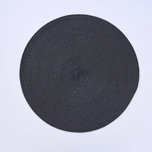 Detail of round black woven placemat featuring intricate spiral texture and heat resistance