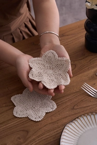 Detail of handmade beige crochet cotton coasters with intricate hollow floral texture