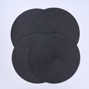 Close-up of four round black woven placemats with heat-resistant spiral texture