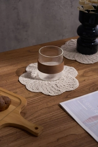 Detailed view of handmade crochet cotton coaster in floral shape on a wooden table