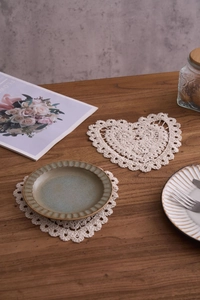 Detailed macro of cream handmade crochet cotton coasters with intricate lace hollow patterns
