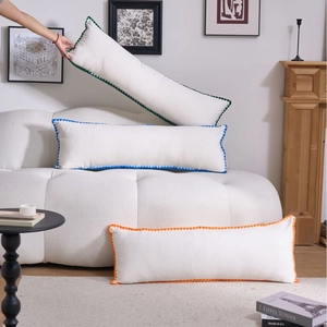Three minimalist white long lumbar pillows with colorful wavy edges on a cozy sofa