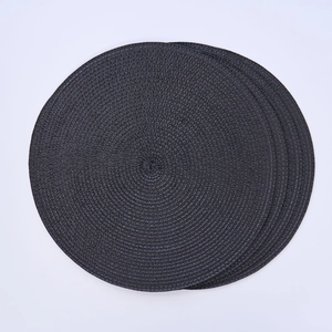 Close-up of black round woven placemat showing detailed spiral texture on white background