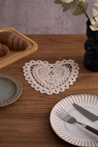 Macro shot of heart-shaped crochet cotton coaster with intricate lace hollow patterns