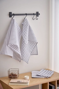 Detail of Nordic plaid and striped kitchen towels with a textured weave on a metal hook