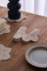 Detail of handcrafted floral crochet cotton coaster in cream with elegant wavy edges