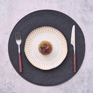 Detail of round dining placemat with ceramic plate and wooden handle cutlery set
