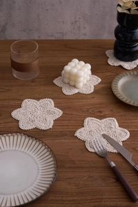 Close-up of handmade beige crochet cotton coasters in floral shape on a wooden table