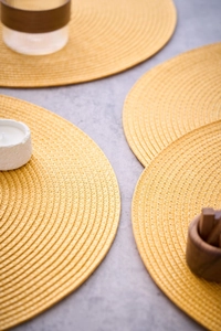 Close-up of ginger yellow round woven PP placemats with heat-resistant spiral texture