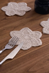Detailed macro view of cream hand-crocheted cotton tea coaster on dark wooden table
