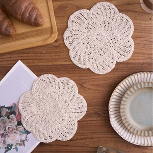 Handmade crochet cotton floral placemats for teapot and cup on deep wood table