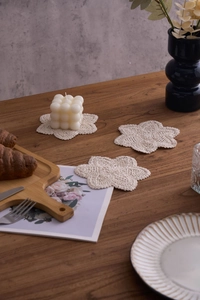 Three handmade crochet cotton coasters in a floral shape on a rustic dark wooden table