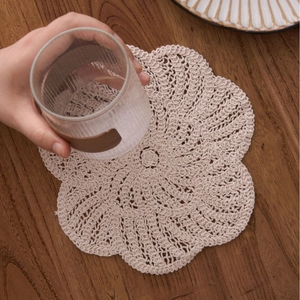 Handmade flower crochet cotton coaster in beige on a rustic wooden tabletop