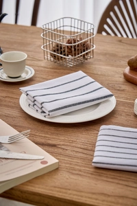 Close-up of blue striped cotton napkins folded neatly on a rustic wooden dining table