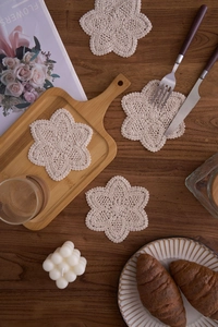 Macro detail of handmade crochet cotton coaster in beige with flower shape petals