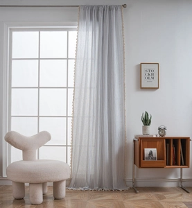 Close-up of semi-blackout curtains with vertical stripes and decorative tassel ball edges