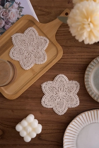 Macro shot of handmade beige snowflake crochet cotton coaster on a wooden texture background