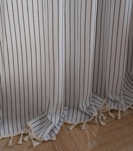 Detail of Nordic plaid curtains with black stripes and decorative beige fringe tassels