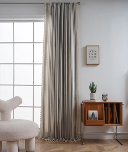 Detail of gray striped linen curtain with elegant side tassels hanging on a window