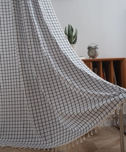 Detail of black and white plaid fabric with elegant beige tassel fringe for curtains