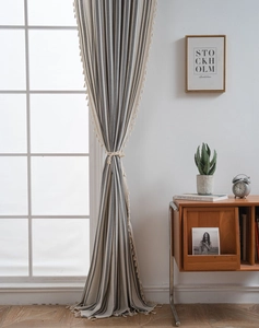 Close-up of gray and white striped fabric curtains featuring elegant beige tassel edges