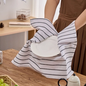 White cotton tea towel with black stripes wrapped around a ceramic plate on a table