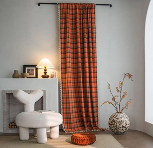 Detail of orange plaid curtain with white tassels on the side in a warm home setting