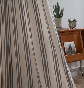 Detailed view of grey and white striped linen fabric curtains with handmade beige tassels