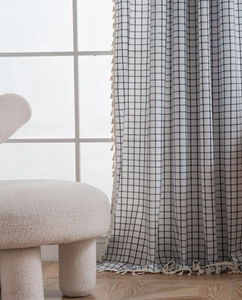Detail of black and white checkered curtain with elegant beige tassel edge trim
