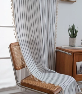 Detail of black and white striped linen curtains with elegant cotton tassels on the edge
