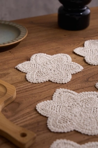 Detail of hand-crocheted beige cotton coasters with elegant floral textured pattern