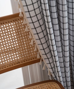 Detail of black and white plaid curtain with elegant cream tassel fringe balls