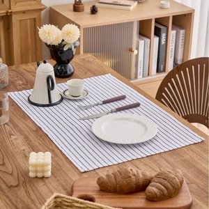 Close-up of a Nordic style white placemat with black stripes on a natural wooden table