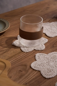 Detailed top view of a handmade crochet cotton coaster with floral edge on a wooden table