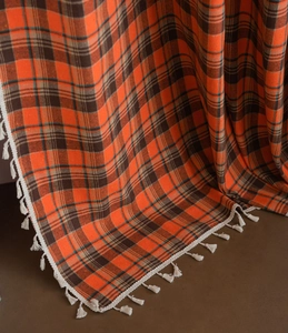 Detailed view of orange and brown checkered fabric with soft white fringe edge