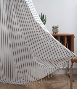 Detail of checkered curtain with black vertical stripes and handmade tassel fringe decor