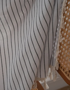 Close-up of beige woven curtain with black vertical stripes and handcrafted tassel details