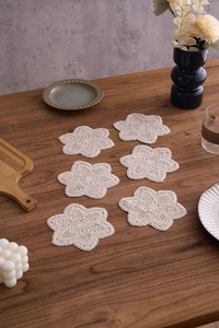 Set of 6 handcrafted cotton crochet coasters in cream flower shape on a dark wood table