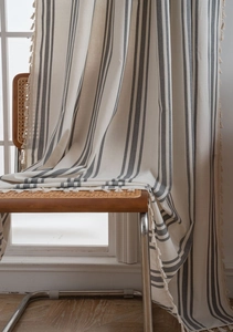 Close-up of French striped cotton linen curtain with decorative fringe edge and tassels