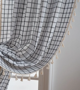 Detail of black and white checkered curtain with elegant cream fringe tassels decoration
