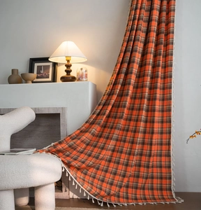 Detailed macro view of orange plaid woven curtain with white tassel fringe decoration