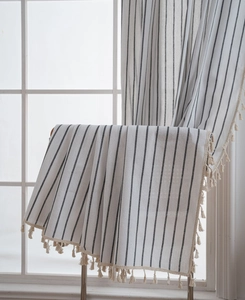 Close-up of minimalist striped linen curtain featuring cream tassel fringe and natural texture